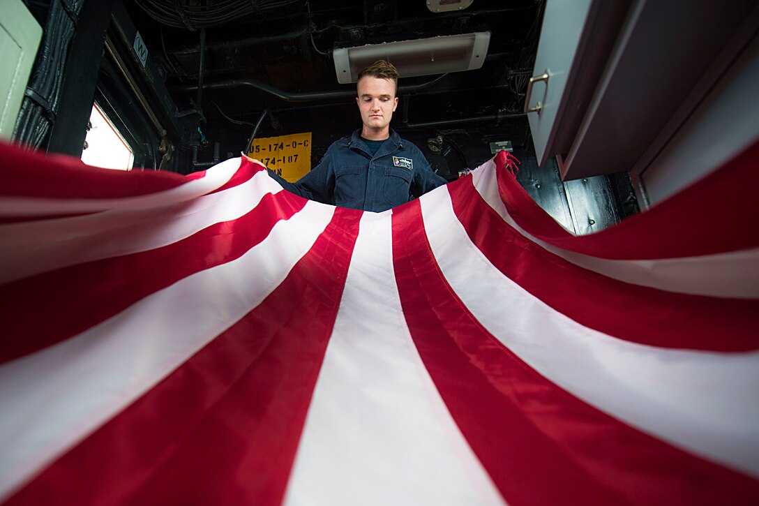 Navy Petty Officer 3rd Class Scott Farrell folds the U.S. flag aboard the guided-missile cruiser USS Chancellorsville in the South China Sea, July 9, 2016. The Chancellorsville is patrolling in the U.S. 7th Fleet area of responsibility supporting security and stability in the Indo-Asia-Pacific region. Navy photo by Petty Officer 2nd Class Andrew Schneider