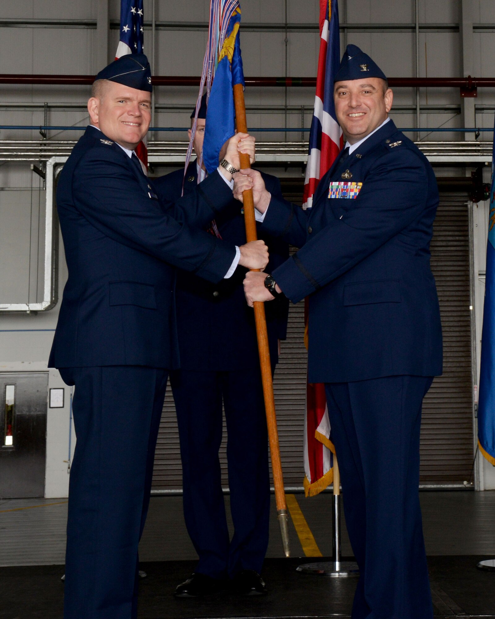 U.S. Air Force Col. Thomas Torkelson, left, 100th Air Refueling Wing commander, passes the guidon to U.S. Air Force Col. Robert Hoskins, right, new 100th Mission Support Group commander, June 29, 2016, during a change of command ceremony on RAF Mildenhall, England. The ceremony is a time-honored tradition in which one officer relinquishes command and passes it to another. (U.S. Air Force photo by Airman 1st Class Tenley Long/Released)