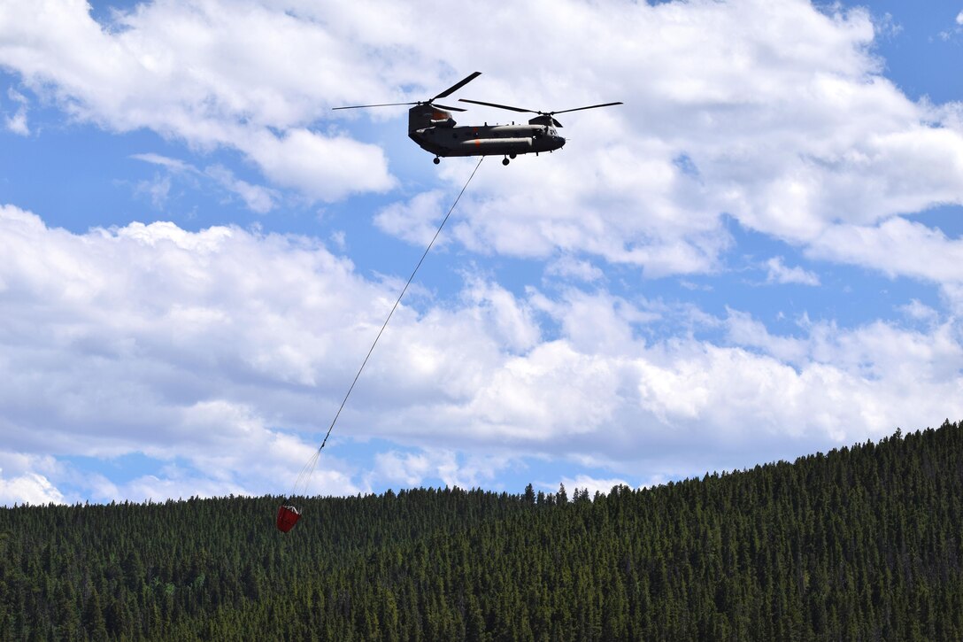 A CH-47 Chinook helicopter takes off after filling up a bucket firefighting system during efforts to battle the Cold Springs fire in Boulder, Colo., July 11, 2016. The helicopter crew is assigned to the Colorado Army National Guard’s 2nd Battalion, 135th General Support Aviation Battalion. Army National Guard photo by Staff. Sgt. Joseph K. VonNida
