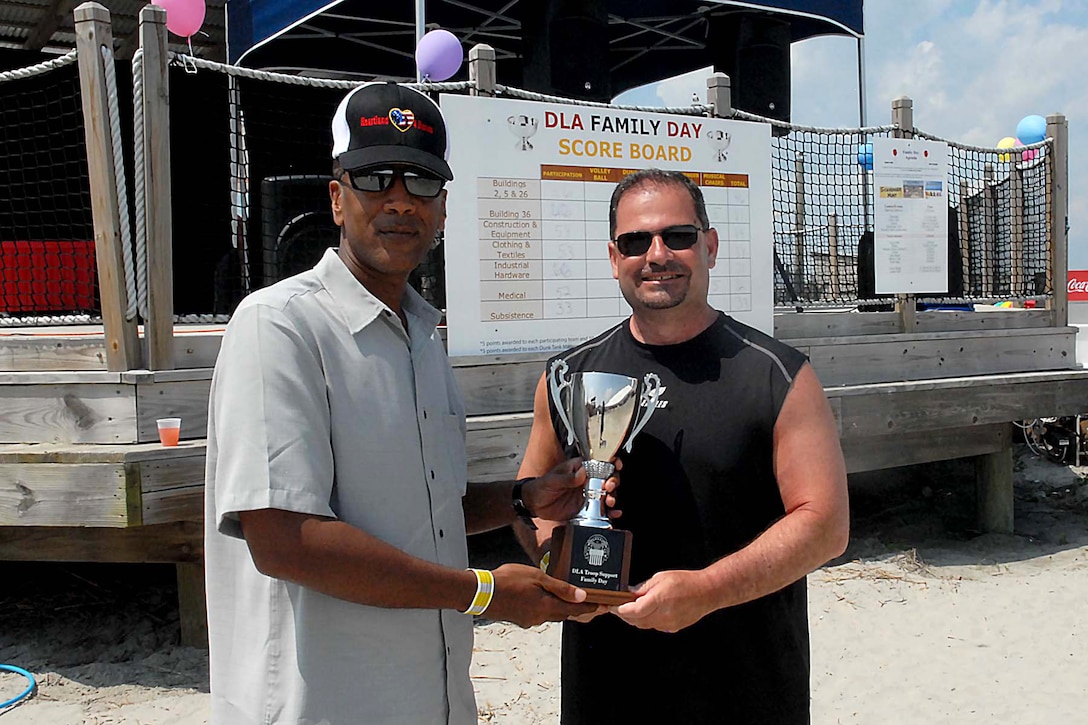 Army Brig. Gen. Charles Hamilton, DLA Troop Support commander (left), presents Anthony D’Ambrosio, Construction and Equipment deputy director, with the Family Day trophy after the supply chain gained the most points during a series of games, including volley ball, musical chairs and quizzo.
