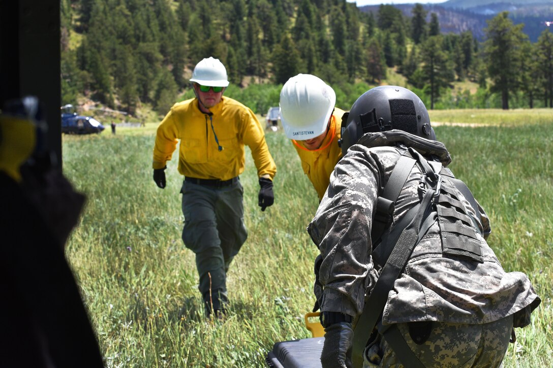 An Army crew chief helps civilian first responders load their equipment into a UH-60 Black Hawk helicopter assisting with the battle against the Cold Springs fire near Nederland, Colo., July 11, 2016. Army National Guard photo by Staff Sgt. Manda Walters