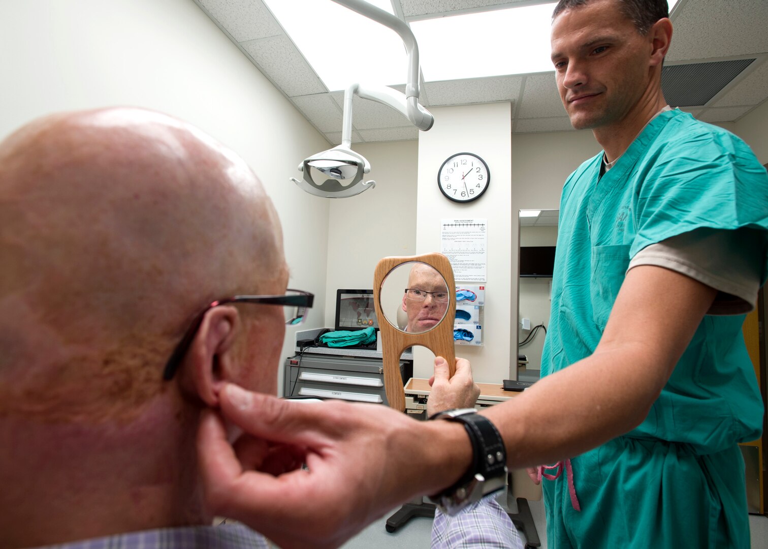 Maj. Stephen Cherrington (right), 59th Dental Group maxillofacial prosthodontist, checks the fitting of retired Army Master Sgt. Todd Nelson’s prosthetic ear at the San Antonio Military Medical Center, Joint Base San Antonio-Fort Sam Houston, Texas, June 28. The 59th Medical Wing's Maxillofacial Prosthetics Department is one of only a few in the Department of Defense that creates prosthetic body parts, such as eyes, ears and noses. (U.S. Air Force photo/Staff Sgt. Kevin Iinuma)