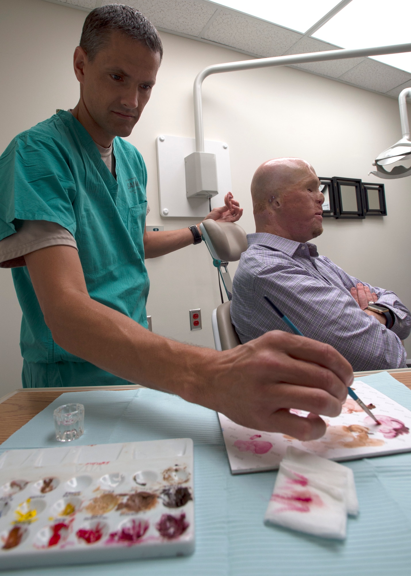 Maj. Stephen Cherrington (left), 59th Dental Group maxillofacial prosthodontist, colors retired Army Master Sgt. Todd Nelson’s new prosthetic ear to match his skin tone at the San Antonio Military Medical Center, Joint Base San Antonio-Fort Sam Houston, Texas, June 28. (U.S. Air Force photo/Staff Sgt. Kevin Iinuma)