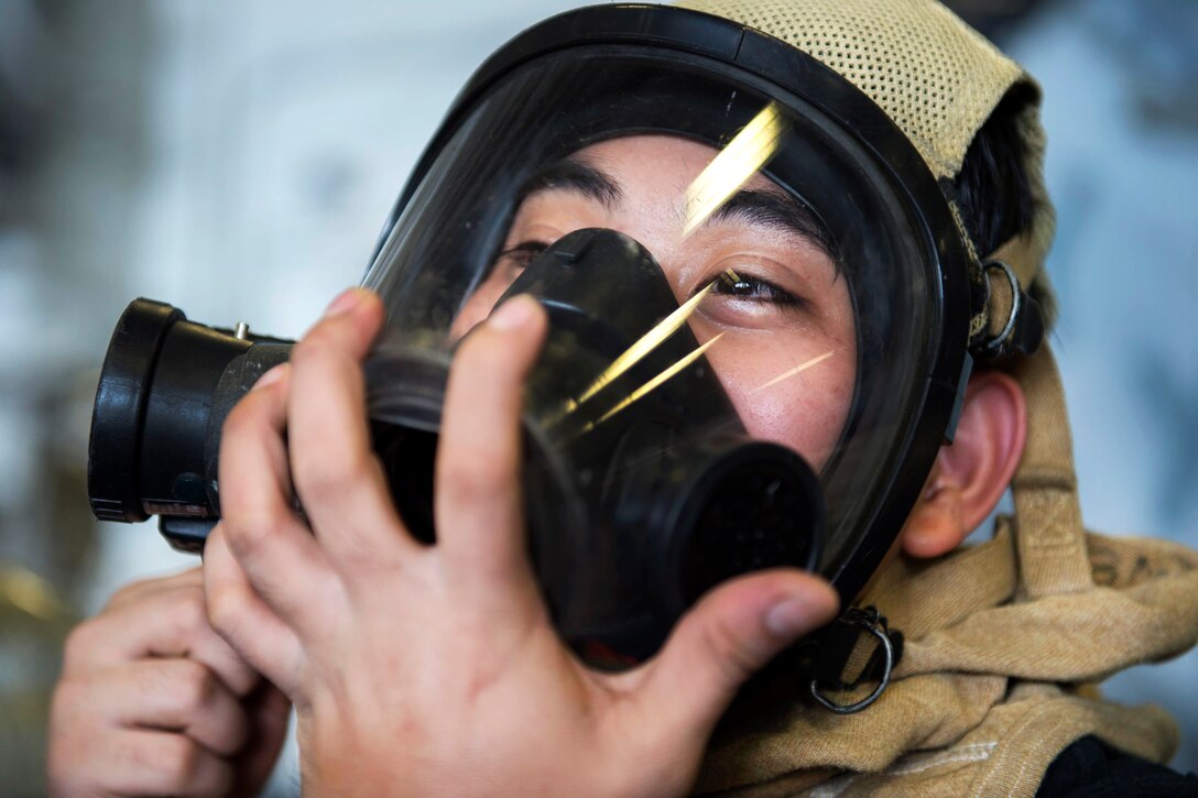 Navy Petty Officer 3rd Class Jason Enjambre checks for an air-tight seal on his self-contained breathing apparatus during a fire drill aboard the amphibious assault ship USS Boxer in the Arabian Gulf, July 9, 2016. Enjambre is a machinery repairman. Navy photo by Petty Officer 2nd Class Debra Daco