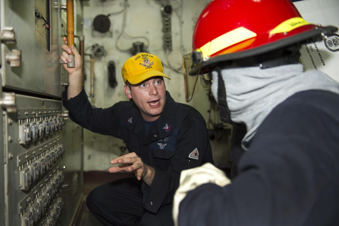 Navy Petty Officer 2nd Class Harley Gaddy, left, instructs Navy Seaman Godfrey Carter during a fire drill aboard the amphibious assault ship USS Boxer in the Arabian Gulf, July 9, 2016. Gaddy is an electrician’s mate and Carter is an electrician’s mate fireman. Navy photo by Petty Officer 2nd Class Debra Daco