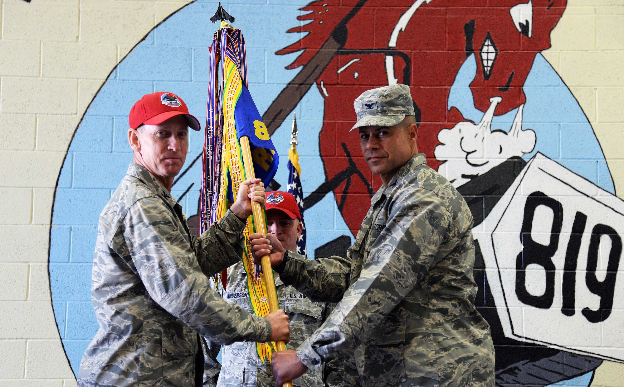 Col. Jose Rivera Hernandez, right, accepts command of the 819th RED HORSE Squadron from Col. Scott Caine, Ninth Air Force vice commander, during a change of command ceremony at the Airfields Hangar July 12. Senior Master Sgt. Paul Anderson, 819th RHS first sergeant, looks on. (U.S. Air Force photo/Airman 1st Class Magen M. Reeves)