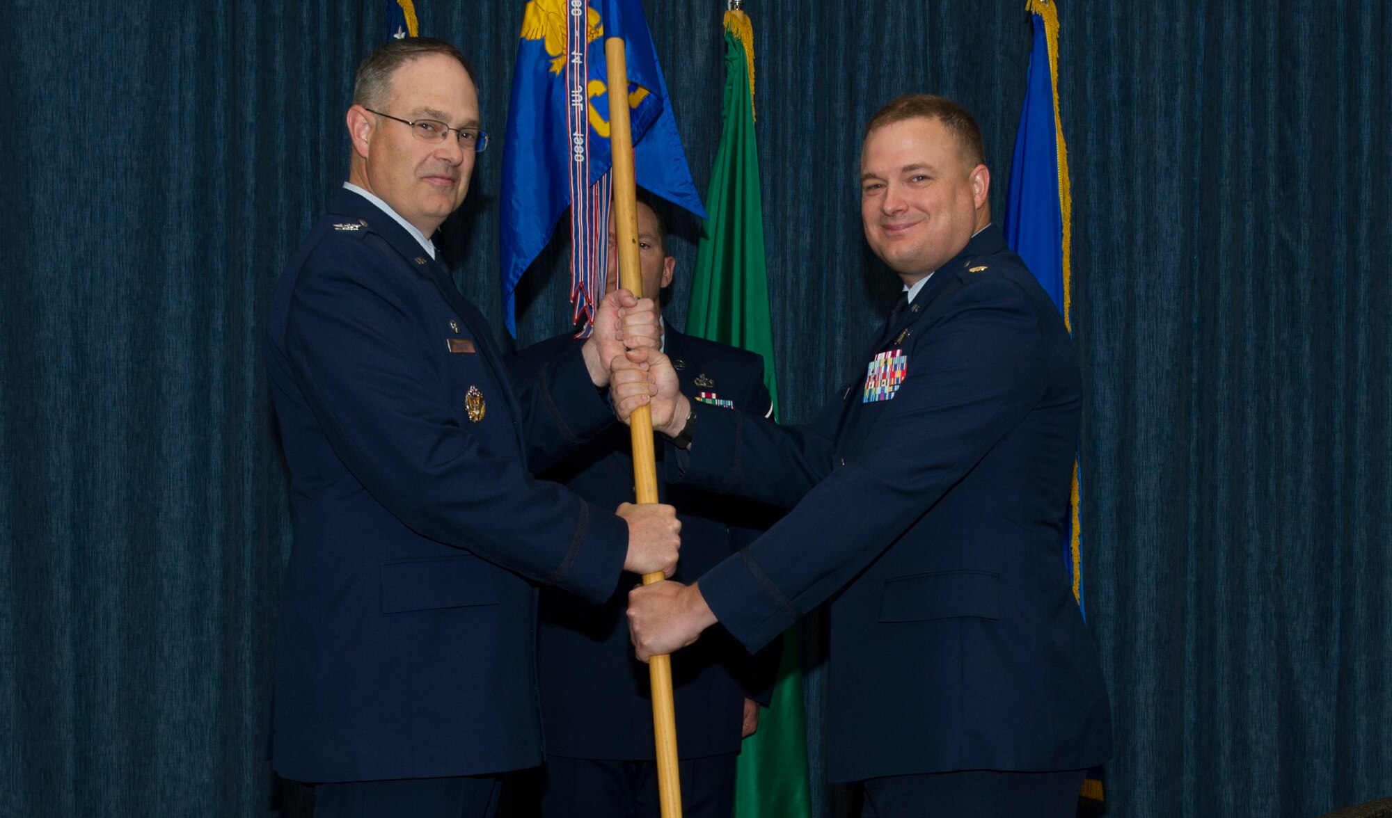 Col. David Stookey, 92nd Mission Support Group commander, passes the 92nd Communications Squadron guidon to Maj. Clayton Baker, 92nd CS commander, during the change of command ceremony July 11, 2016, at Fairchild Air Force Base, Wash. Baker was previously at the office of the Secretary of the Air Force. (U.S. Air Force photo/Senior Airman Nick J. Daniello) 