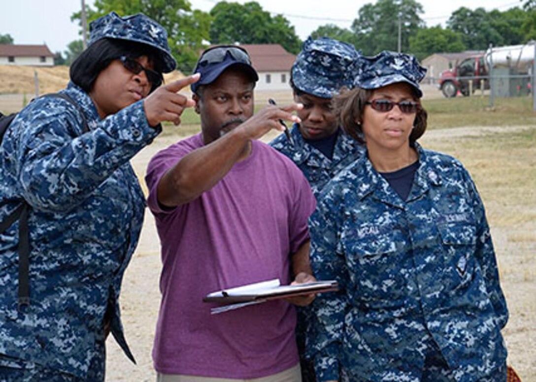 Navy Logistics Specialist 2nd Class Nicole Collins, Material Examiner Mike Hambrick, Navy Logistics Specialist 2nd Class Clarice Johnson and Navy Logistics Specialist 2nd Class Tracy McCall discuss the plan for their team’s expeditionary disposition site build during training at Fort Custer National Guard Base.