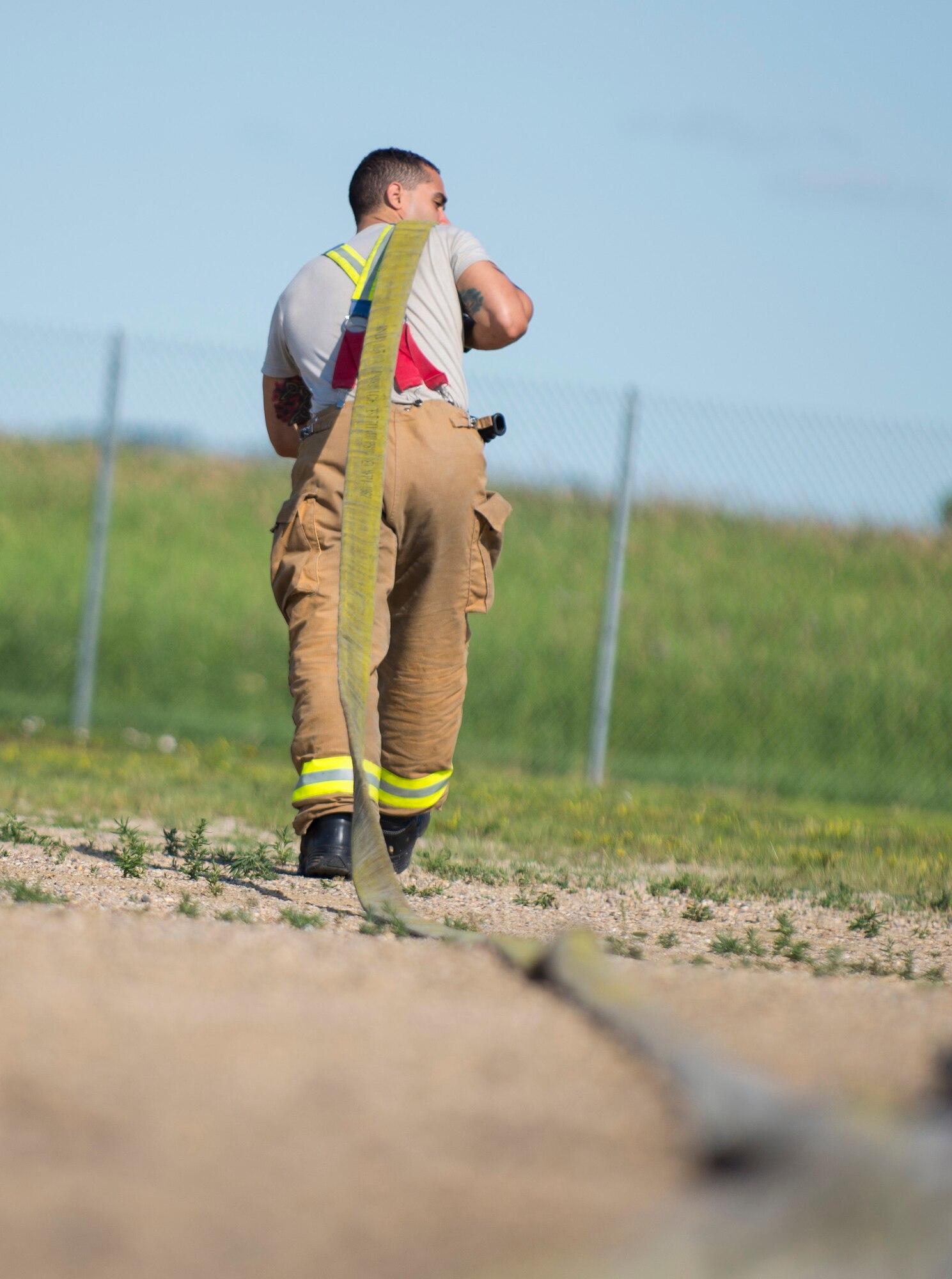 Airman 1st Class Roberto Vazquez, 5th Civil Engineer Squadron firefighter, pulls a fire hose in preparation for live fire exercise at Minot Air Force Base, N.D., July 8, 2016. The fire department trains regularly to maintain readiness. (U.S. Air Force photo/Airman 1st Class Christian Sullivan)