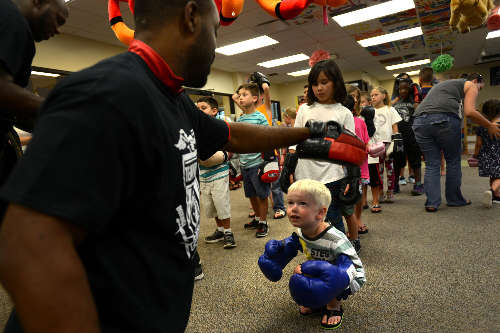 A Team Shaw child ducks under a simulated strike from a member of Team Robinson MMA at the McElveen Information and Learning Center at Shaw Air Force Base, S.C., June 24, 2016. More than 100 children participated in the demonstration, intended to teach basic self-defense and support the library’s summer reading program. (U.S. Air Force photo by Airman 1st Class Kelsey Tucker)