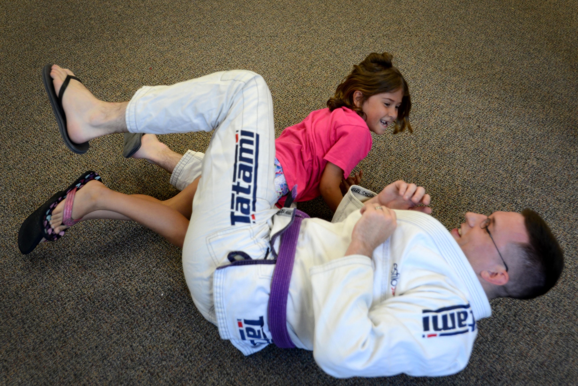 A Team Shaw child practices a Brazilian Jiu-Jitsu move on Senior Airman Jeffrey Weber, 51st Intelligence Squadron analyst, during a summer reading program event at the McElveen Information and Learning Center at Shaw Air Force Base, S.C., June 24, 2016. Children who attended the summer reading program event took part in various martial arts activities, such as learning how to escape from being pinned to the ground. (U.S. Air Force photo by Airman 1st Class Kelsey Tucker)