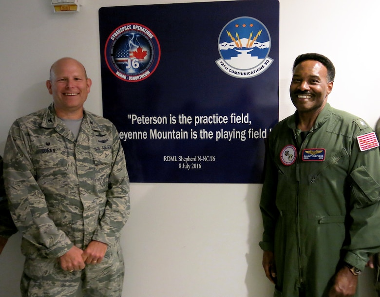 CHEYENNE MOUNTAIN AIR FORCE STATION, Colo. – Rear Adm. Dwight Shepherd, North American Aerospace Defense and United States Northern Command cybersystems director, right, and Col. Gary Cornn, Cheyenne Mountain Air Force Station commander, present the newly unveiled sign honoring Shepherd’s work related to network and software upgrades to the installation July 8, 2016. The quote was used to keep Shepehrd’s team on track as the project is underway. (Courtesy photo)