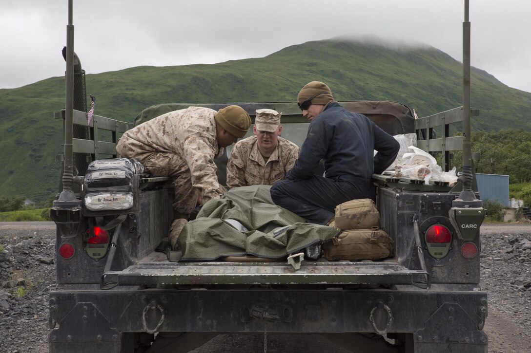 Petty Officer 3rd Class Jerry S. Pring (left), a hospital corpsman with Detachment B, Marine Wing Support Squadron-472, Marine Aircraft Group 49, 4th Marine Aircraft Wing, Marine Forces Reserve, Lance Cpl. David J. Rowe (center), an aircraft rescue and firefighting specialist with Det. B, MWSS-472, and Lance Cpl. Benjamin A. Bakker (right), an automotive maintenance technician with Engineer Support Company, 6th Engineer Support Battalion, 4th Marine Logistics Group, simulate a casualty evacuation at Innovative Readiness Training Old Harbor, Alaska, July 9, 2016. IRT Old Harbor is part of a civil and joint military program to improve military readiness while simultaneously providing quality services to underserved communities throughout the United States. (U.S. Marine Corps photo by Sgt. Ian Leones/Released) 