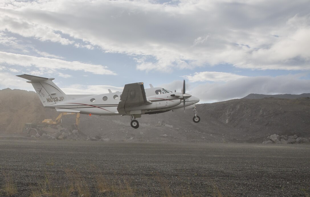 A civilian aircraft takes off while Marines from across Marine Forces Reserve move material in the background to construct a 2,000 foot extension to the existing Old Harbor airport runway during Innovative Readiness Training Old Harbor, Alaska, July 10, 2016. The Marines are building the runway to make it possible for larger aircraft to land. IRT Old Harbor is part of a civil and joint military program to improve military readiness while simultaneously providing quality services to underserved communities throughout the United States. (U.S. Marine Corps photo by Sgt. Ian Leones/Released)