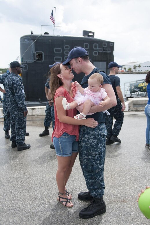 SANTA RITA, Guam (July 1, 2016) Machinist's Mate Weapons 2nd Class Jeramy Coleman, right, holds his daughter, Sage, and kisses his wife, Liz, on the pier during a homecoming ceremony for the Los Angeles-class attack submarine USS Topeka (SSN 754). Topeka arrived at Polaris Point for its first Guam homecoming following a two-month forward operating period to the Western Pacific. (U.S. Navy photo by Lieutenant Lauren Spaziano/Released)