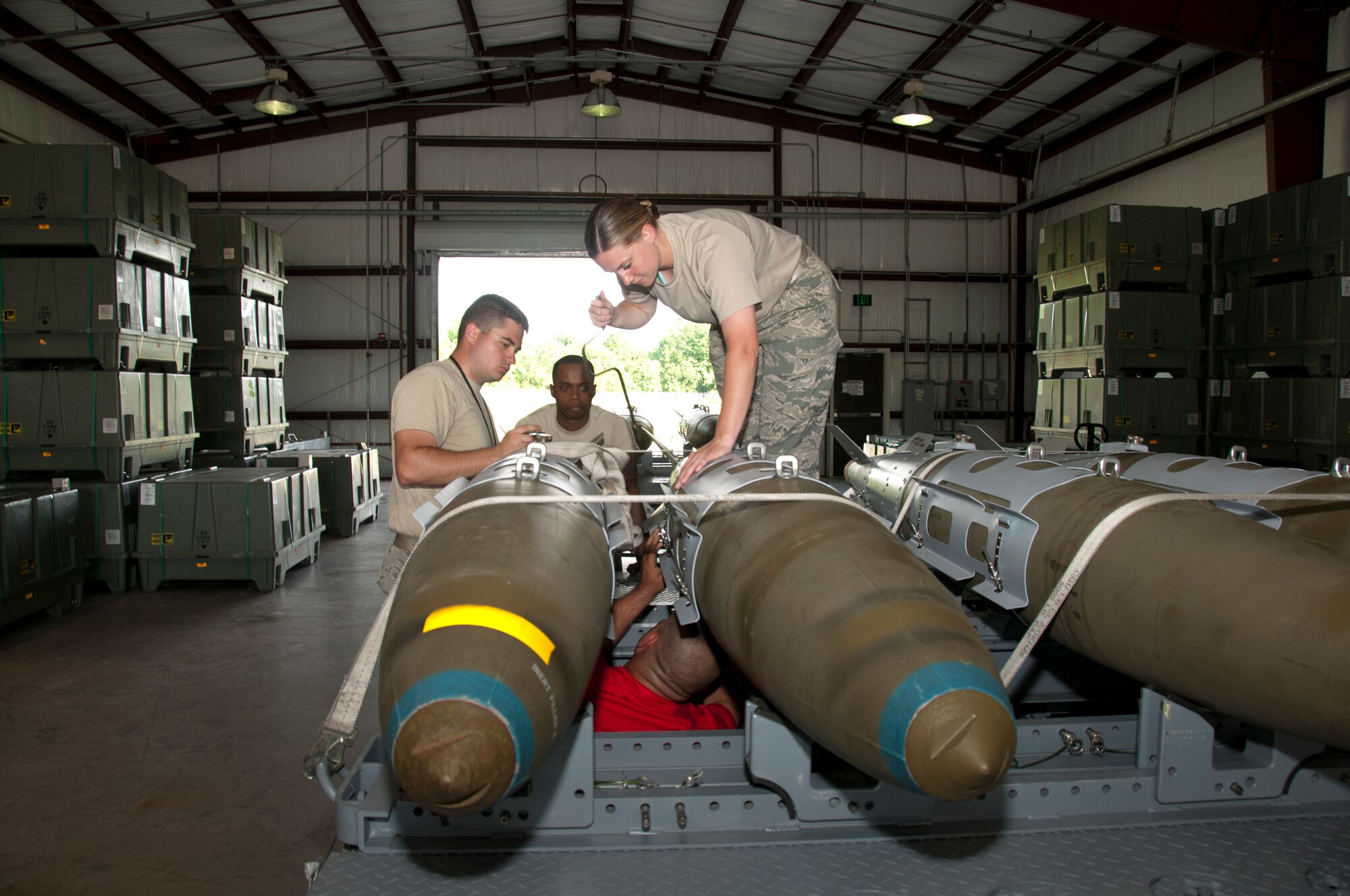 U.S. Air Force Airman 1st Class Randal Trosky, 1st Maintenance Squadron, Tech. Sgt. Kenneth Stanley and Staff Sgts. Louis Jackson and Kerri White, 192nd MXS, ordnance maintenance mechanics, train together while building eight Mark 83 inert bombs for an exercise commemorating Maj. Gen. Billy Mitchell’s bombing of the German battleship Ostfriesland, at Langley Air Force Base, Va., July 10, 2016. Virginia Air National Guard and Active Duty Air Force members often work together as part of total force integration. Air Force personnel are scheduled to build an additional 24 inert bombs for the exercise.  (U.S. Air National Guard photo by Master Sgt. Carlos J. Claudio)