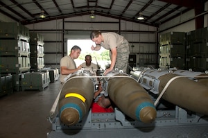 U.S. Air Force Airman 1st Class Randal Trosky, 1st Maintenance Squadron, Tech. Sgt. Kenneth Stanley and Staff Sgts. Louis Jackson and Kerri White, 192nd MXS, ordnance maintenance mechanics, train together while building eight Mark 83 inert bombs for an exercise commemorating Maj. Gen. Billy Mitchell’s bombing of the German battleship Ostfriesland, at Langley Air Force Base, Va., July 10, 2016. Virginia Air National Guard and Active Duty Air Force members often work together as part of total force integration. Air Force personnel are scheduled to build an additional 24 inert bombs for the exercise.  (U.S. Air National Guard photo by Master Sgt. Carlos J. Claudio)