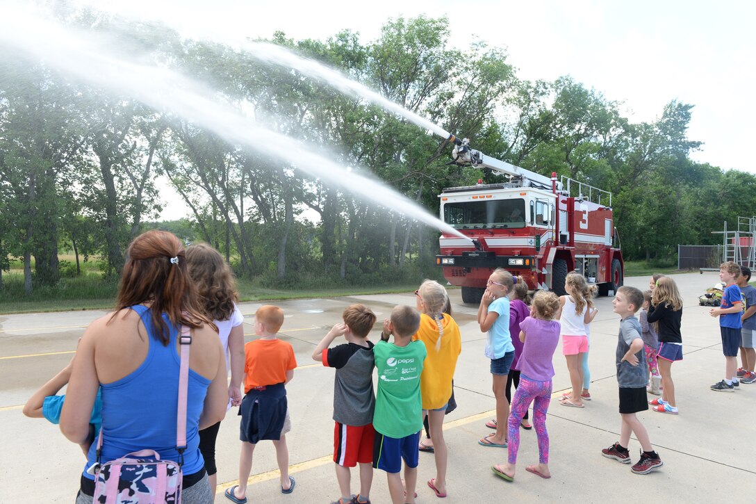 Master Sgt. Chad Noyes, a 119th Wing fire fighter, sprays the fire truck turrets for a group of children during a tour at the North Dakota Air National Guard Base, Fargo, North Dakota, July 7, 2016. (U.S. Air National Guard Photo by Senior Master Sgt. David H. Lipp/Released)