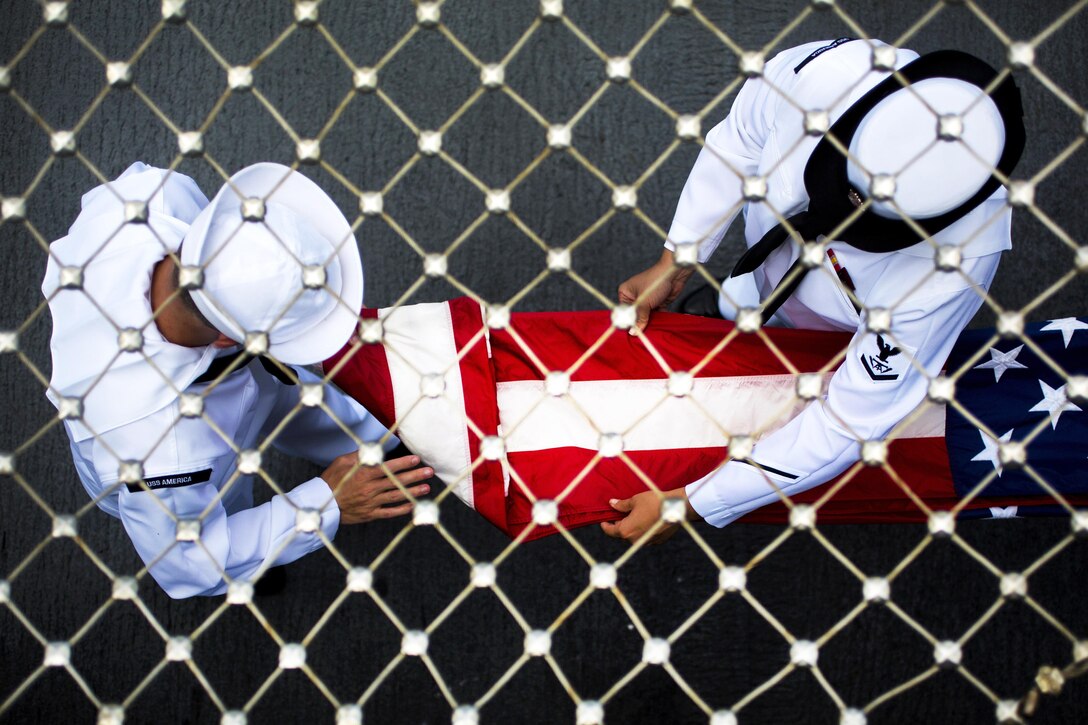 Sailors fold the American flag to prepare for the USS America to leave port during Rim of the Pacific 2016 in Pearl Harbor, Hawaii, July 12, 2016. Twenty-six nations, 49 ships, six submarines, about 200 aircraft and 25,000 personnel are participating in the exercise in Hawaii and Southern California. Marine Corps photo by Cpl. Isaac Ibarra