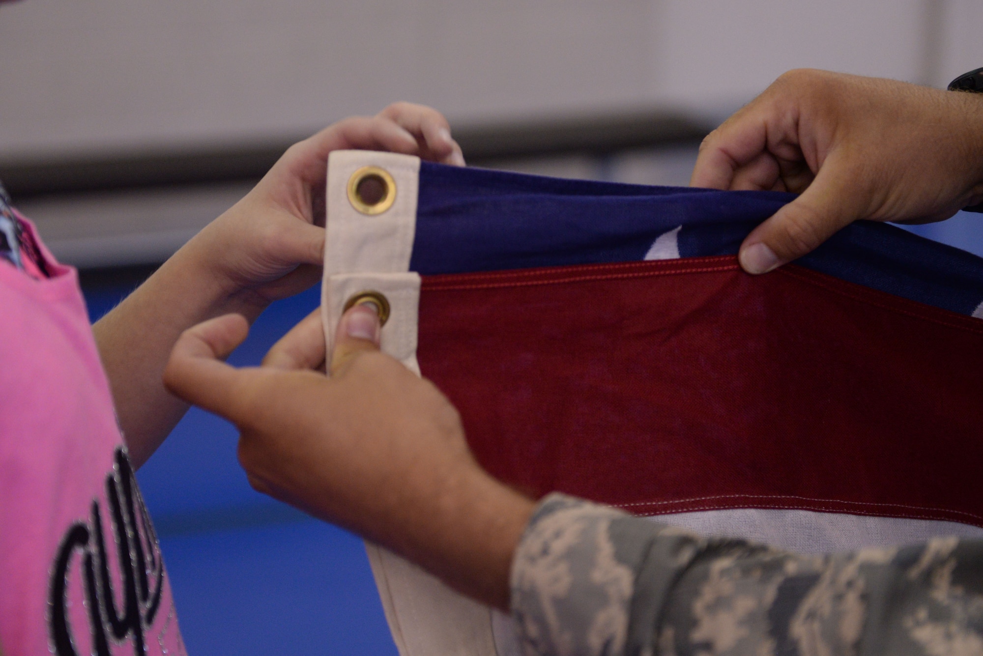 An Honor Guard Airman shows a military child how to measure the flag for a proper fold during the Youth Center Boot Camp at Minot Air Force Base, N.D., July 7, 2016. Children learned the proper customs and courtesies when folding an American Flag. (U.S. Air Force photo/Airman 1st Class Jessica Weissman)
