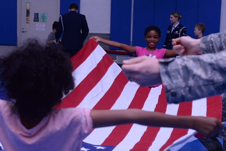 Demya Hill opens the flag before refolding it at the Youth Center Boot Camp at Minot Air Force Base, N.D., July 7, 2016. Students participated in physical fitness, drill and survival training during the week-long camp. (U.S. Air Force photo/Airman 1st Class Jessica Weissman)