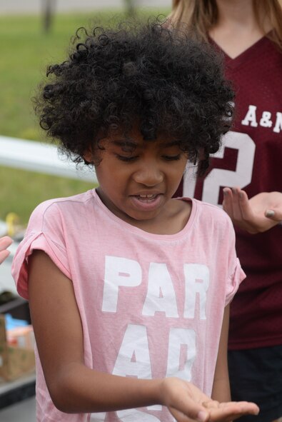 Ariana Montgomery holds a flavored cricket during Survival, Evasion, Resistance and Escape training during the Youth Center Boot Camp at Minot Air Force Base, N.D., July 7, 2016. Children were able to taste bugs, observe homemade tools and learn about obtaining sustenance in a real-life survival situation. (U.S. Air Force photo/Airman 1st Class Jessica Weissman)