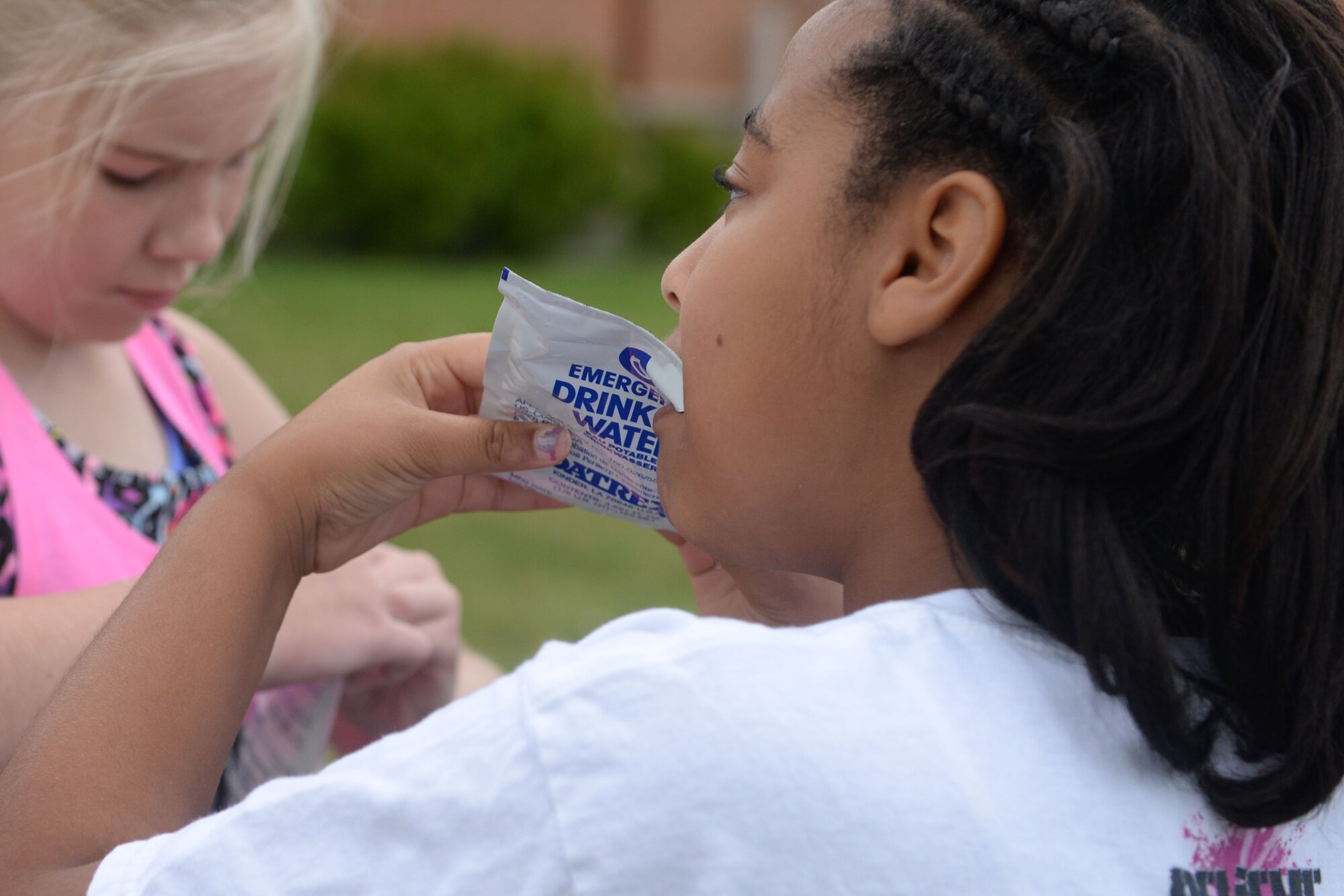 Military children drink water from pouches like those given to pilots and air crew members during Youth Boot Camp at Minot Air Force Base, N.D., July 7, 2016. Children were shown equipment given to pilots and air crew members, and instructed on what each piece of equipment does. (U.S. Air Force photo/Airman 1st Class Jessica Weissman)