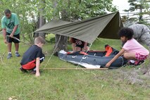Military children finalize their make-shift shelter during survival training at the Youth Center Boot Camp at Minot Air Force Base, N.D., July 7, 2016. Children learned how to make tools, obtain sustenance and create fire during a simulated survival situation. (U.S. Air Force photo/Airman 1st Class Jessica Weissman)