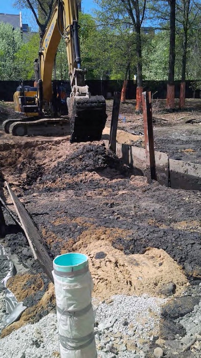 Excavator mixing saw dust into the river sediment to help solidify the material for transport off-site.