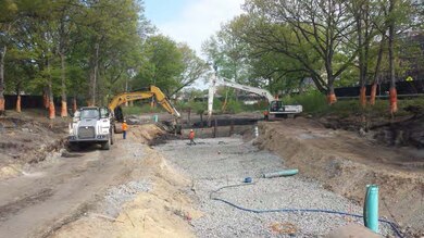 Temporary access roads are constructed on either side of the river bank in order to remove the sediment (black material in the background where the excavators are working) from the river channel bottom – end of April 2015.