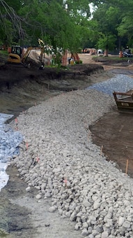 Looking downstream at Upper Fens Pond. Note the construction of the stone protection at the toe of the bank – mid June 2015.