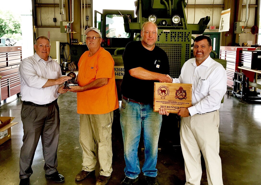 81st Regional Support Command Director of Logistics Ardis Ferguson presents John White with a trophy  while his deputy, Gregg Charvoz presents George Boy with a plaque recognizing the shop’s achievements. Area Maintenance Support Activity 147G won the USARC-level Army Award for Maintenance Excellence and is competing at the Department of the Army Level.