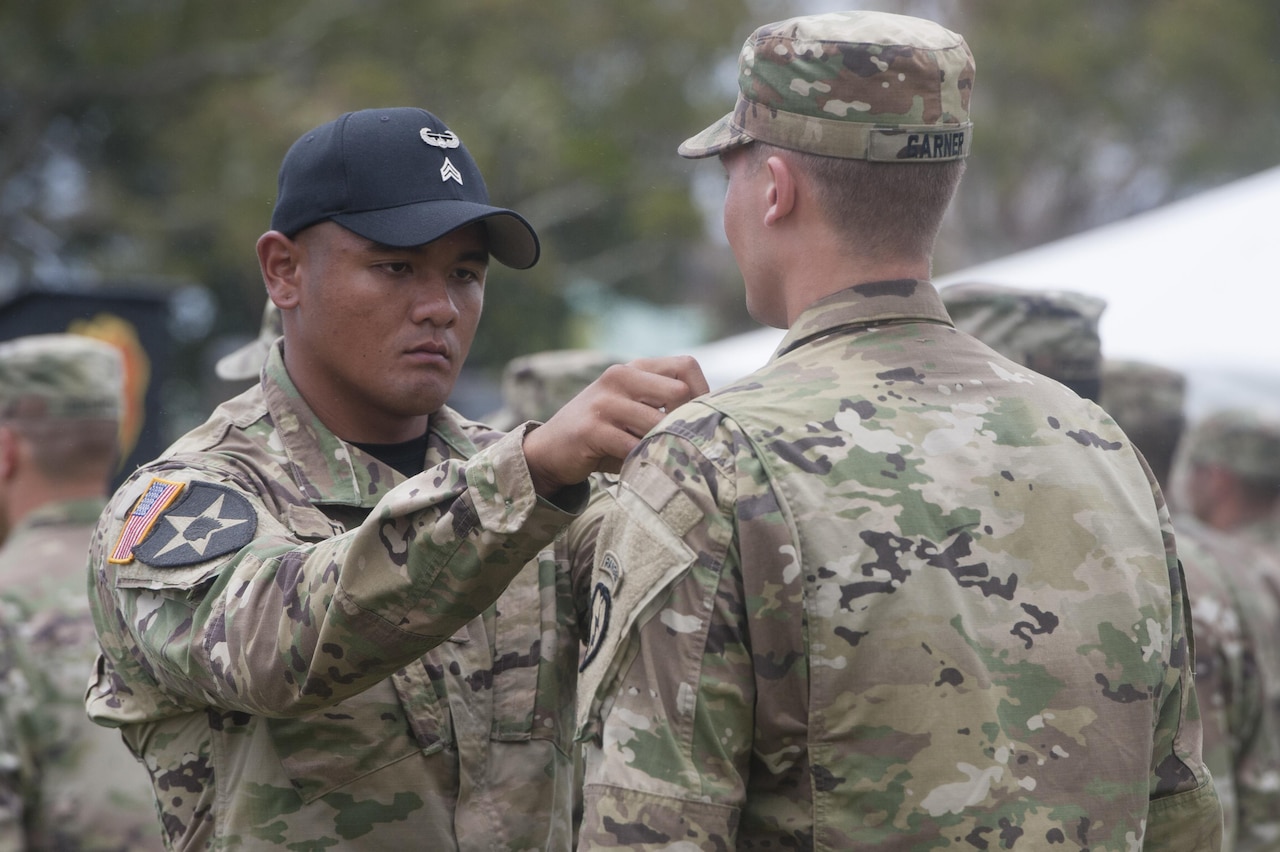 Army Sgt. Samnith Thy presents a soldier with the Air Assault Badge during an Air Assault School graduation ceremony June 6, 2016, at Schofield Barracks, Hawaii. Air Force photo by Staff Sgt. Christopher Hubenthal