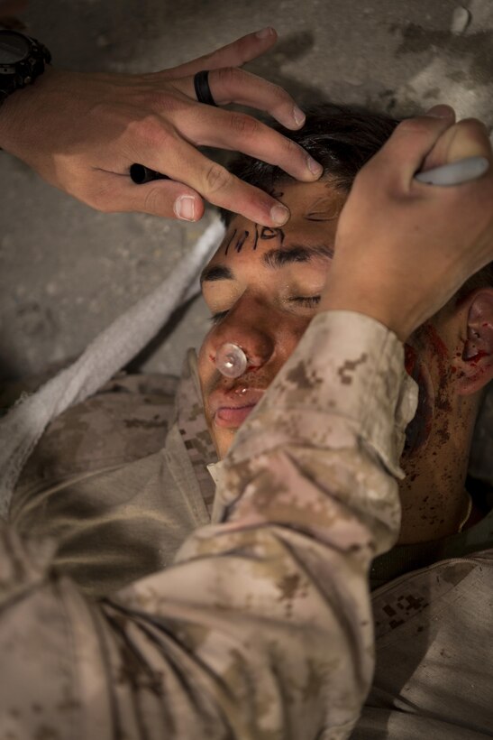 A U.S. Marine writes the time a tourniquet is applied to Cpl. Joe Tamayo, a heavy equipment operator, both with
Company C, Marine Wing Support Squadron 373, Special Purpose Marine Air Ground Task Force – Crisis Response - Central Command , during the final exam of a combat lifesaver, June 17, 2016. SPMAGTF-CR-CC is currently forward deployed in several host nations, with the ability to respond, rapidly, to a variety of contingencies. (U.S. Marine Corps photo by Sgt. Donald Holbert/ Released)