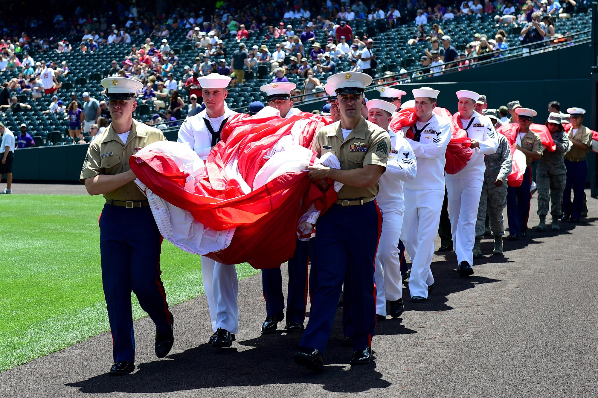 Service members carry out an American flag July 10, 2016, during a military appreciation ceremony at a Colorado Rockies game at Coors Field in Denver. The ceremony brought together members from every branch of the military to honor those who have served or are currently serving in the military. (U.S. Air Force photo by Airman 1st Class Gabrielle Spradling/Released)