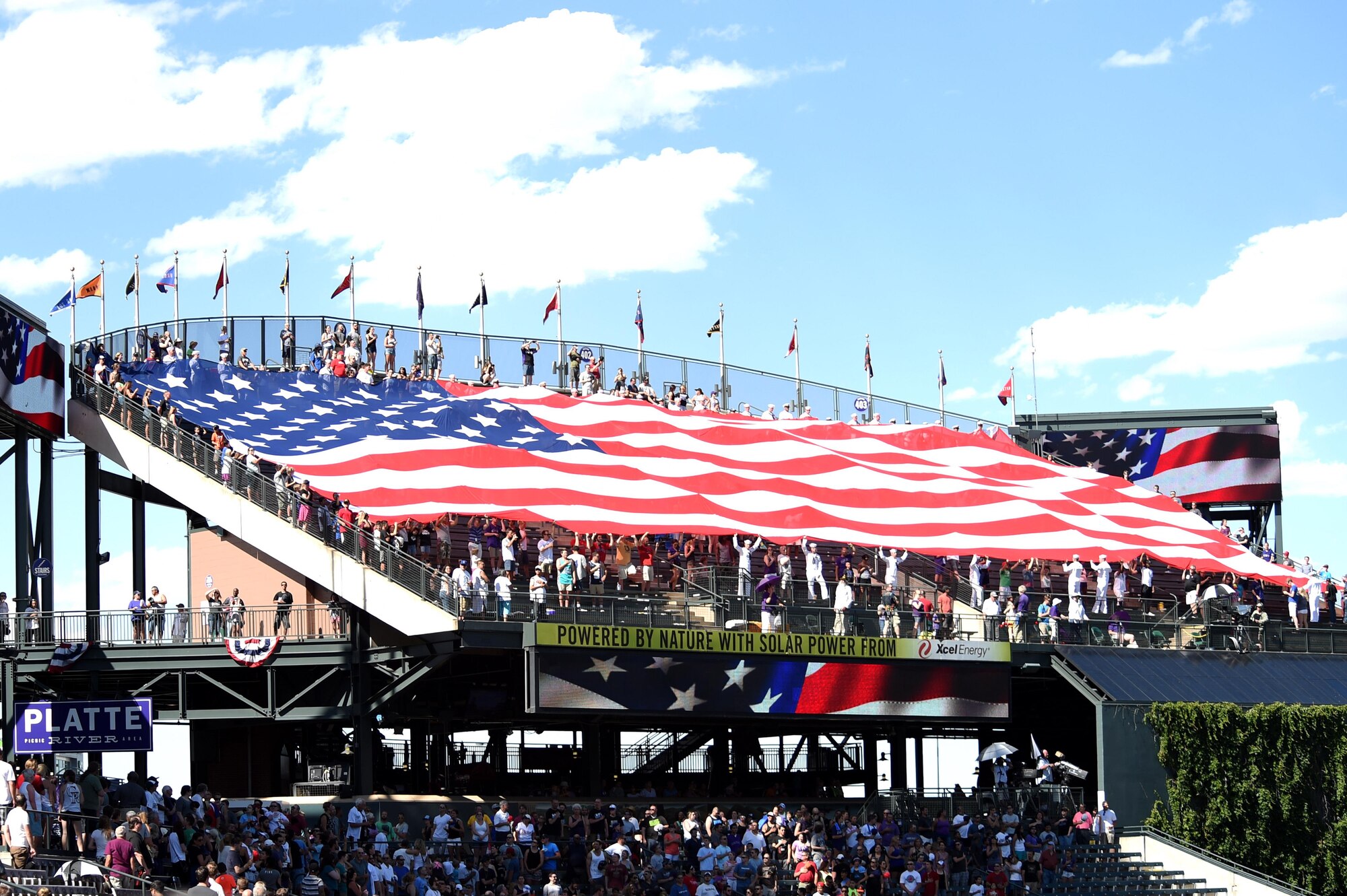 Service members unravel an American flag July 10, 2016, during the seventh inning stretch at a Colorado Rockies military appreciation game at Coors Field in Denver, Colo. The ceremony provided an opportunity to recognize Service members from every branch and their sacrifices. (U.S. Air Force photo by Airman 1st Class Gabrielle Spradling/Released)