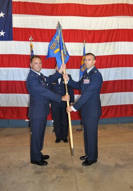 (Right) Lt. Col. Agustin Carrero receives the 379th Space Range Squadron guidon from Col. Dean Caldwell, 926th Operations Group commander, upon becoming the squadron's new commander during a change of command ceremony at the Range Space Facility, Colorado Springs, Colorado, on July 9. (U.S. Air Force photo/Maj. Jessica D'Ambrosio)