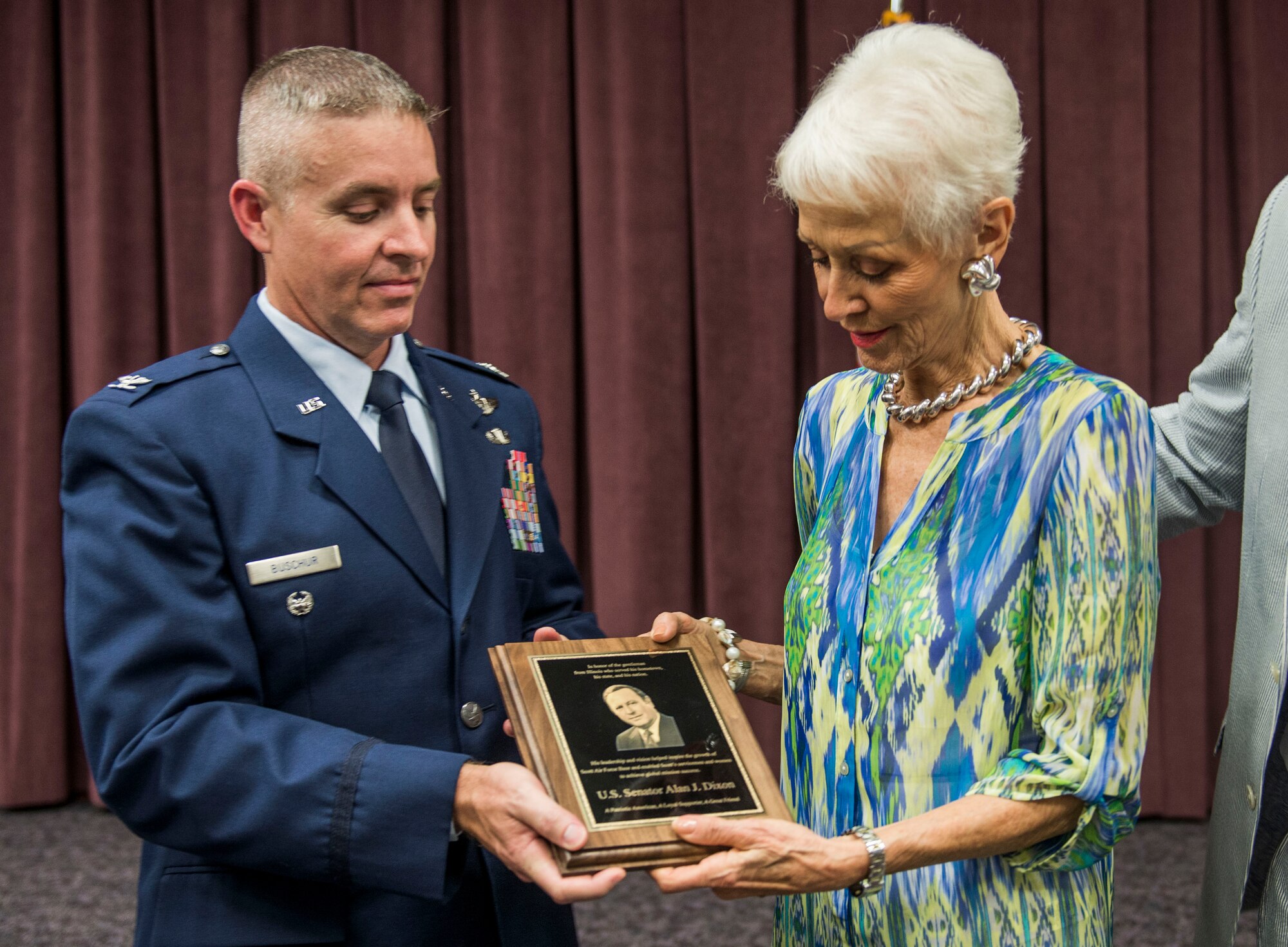 Col. Chris Buschur, 375th Mobility Wing vice commander, presents former Ill. Sen. Alan J. Dixon's wife, Jody, with a plaque honoring her husband at Scott Air Force Base, Ill., July 8, 2016. The visitor center was dedicated to Dixon, who gave 43 years of public service to Scott AFB and the state of Ill. (U.S. Air Force photo by Jodi Martinez/Released)