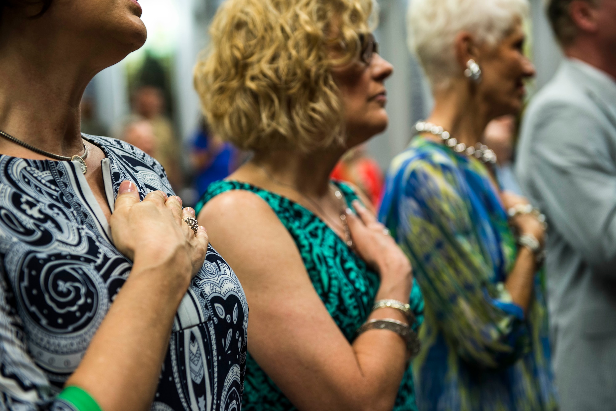 Ill. Sen. Alan J. Dixon's daughters, Elizabeth Megaw and Dr. Stephanie Yearian, and his wife, Jody Dixon, cover their hearts during the singing of the national anthem for the dedication ceremony of Sen. Dixon at Scott Air Force Base, Ill., July 8, 2016. The visitor center was dedicated to Dixon, who gave 43 years of public service to Scott AFB and the state of Ill. (U.S. Air Force photo by Jodi Martinez/Released)