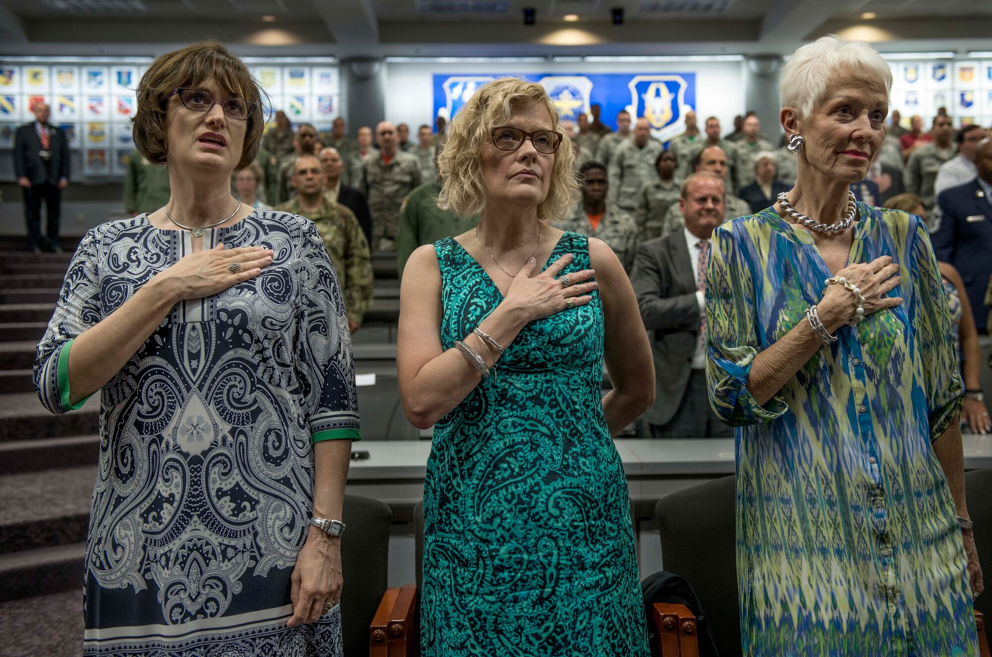 Ill. Sen. Alan J. Dixon's daughters, Elizabeth Megaw and Dr. Stephanie Yearian, and his wife, Jody Dixon, cover their hearts during the singing of the national anthem for the dedication ceremony of Sen. Dixon at Scott Air Force Base, Ill., July 8, 2016. The visitor center was dedicated to Dixon, who gave 43 years of public service to Scott AFB and the state of Ill. (U.S. Air Force photo by Jodi Martinez/Released)