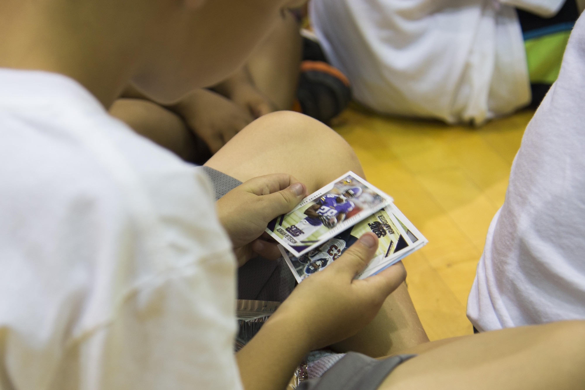 A child from Team Scott looks through a deck of football cards during the Steve Smith Pro Camp event July 6, 2016 at Scott Air Force Base, Ill. Each camper received a pack of football cards, an autograph from Steve Smith, a photo of their team,  and a limited edition P&G Steve Smith, Sr. Football ProCamp t-shirt. (U.S. Air Force photo by Airman 1st Class Gwendalyn Smith)