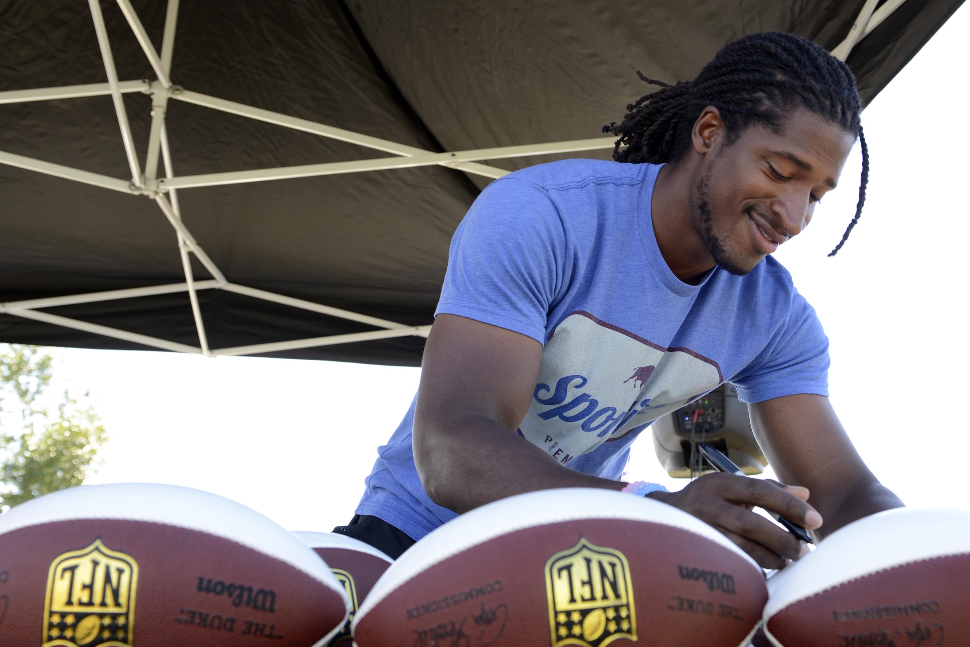 Andre Roberts, a wide receiver with the Detroit Lions, autographs a football at the Military ProCamp at Joint Base Elmendorf-Richardson, Alaska, June 12, 2016. The 2016 ProCamp visit marked Roberts’ return to his birth state, after an almost 26-year absence. (U.S. Air Force photo by Airman 1st Class Javier Alvarez)