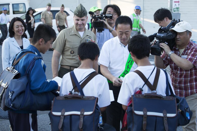 The Honorable Yoshihiko Fukuda, mayor of Iwakuni, right, hands out fliers to local Japanese students while walking with U.S. Marine Corps Col. Robert V. Boucher, commanding officer of Marine Corps Air Station Iwakuni, during the seventh Joint Leadership Walk down the streets of Iwakuni on July 6, 2016. The last walk took place in December 2015 and continues to be a firm demonstration of the bond and unity between both communities. (U.S. Marine Corps photo by Lance Cpl. Donato Maffin/Released