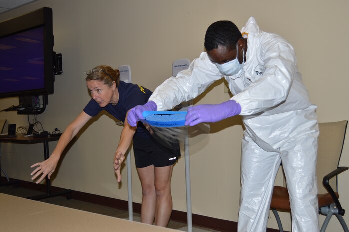 Capt. Robin Lewis, U.S. Public Health Service Corps offer and psychologist serving at Naval Health Clinic Charleston, trains Chief Petty Officer Anthony Johnson, yeoman and NHCC Substance Abuse Rehabilitation Program (SARP) Counselor, to remove personal protective equipment during Ebola response training Aug. 28, 2015 at NHCC. (Navy photo/ Kris Patterson)