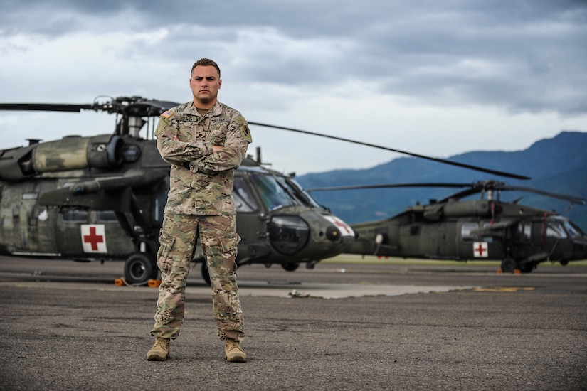 U.S. Army Spc. Tyler Holman, a combat medic assigned to the 1st Battalion, 228th Aviation Regiment, poses for a photo in front of two UH-60 Black Hawks at Soto Cano Air Base, Honduras, July 12, 2016. While on leave in Roatán, Honduras, Holman save the life of a Honduran teen who was unresponsive on the beach. (U.S. Air Force photo by Staff Sgt. Siuta B. Ika)