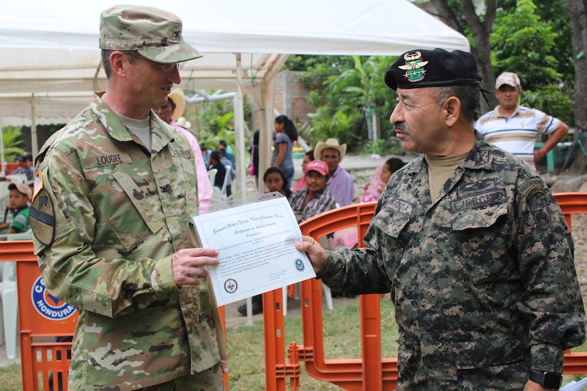 Comayagua, Honduras – U.S. Army Col. Douglas Lougee (left), Joint Task Force-Bravo Medical Element commander, presents Honduran Army Col. Julio Cesar Urquia (right), Director of the Experimental Center of Agricultural Development and Ecological Conservation (CEDACE), with a certificate of appreciation for the professional exchange and mutual support during a Military Partnership Engagement in San Sebastian, Comayagua, Honduras, July 9, 2016. JTF-Bravo participated at the request of the CEDACE Director, providing an opportunity for JTF-Bravo to assist the Honduran military in providing humanitarian aid to locals, as well as a chance for service members to train and prepare for a humanitarian crisis in support of U.S. partner nations in Central America. (U.S. Army photo by Maria Pinel)