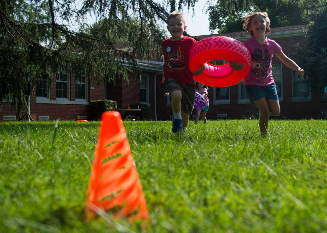 Two children run with an inner tube during a team building exercise during Vacation Bible School at Fort Eustis, Va., July 12, 2016. Children rotated through different games as well as crafts and studies, all of which exemplified the week’s lessons and working together. (U.S. Air Force photo by Staff J.D. Strong II)