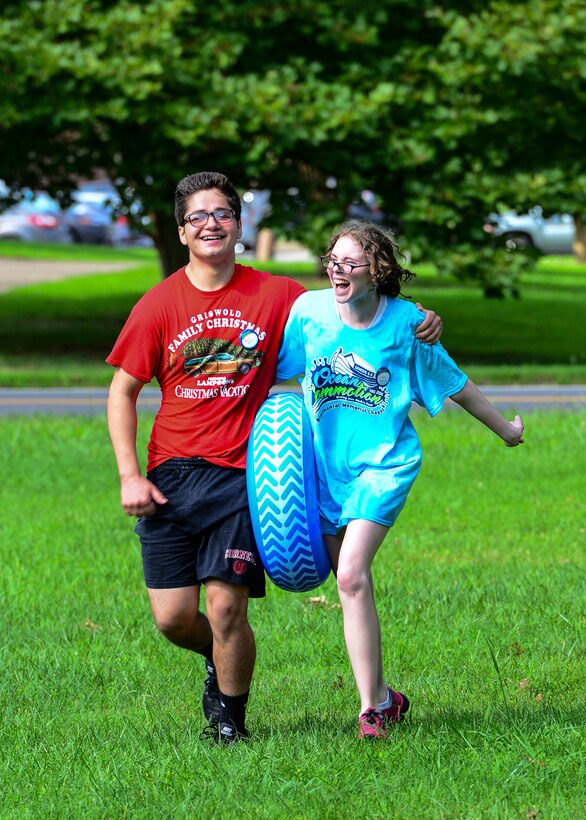 Mark Crate and Lola Gillet, Vacation Bible School youth volunteers, together, run a tire across the field during a teamwork event at Fort Eustis, Va., July 12, 2016. The purpose of the Vacation Bible School is to bring military families together while educating them on support programs and other opportunities the chapel offers. (U.S. Air Force photo by Staff J.D. Strong II)