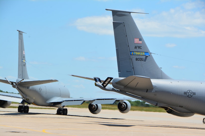 Two aircraft taxi in different directions on a flight line.