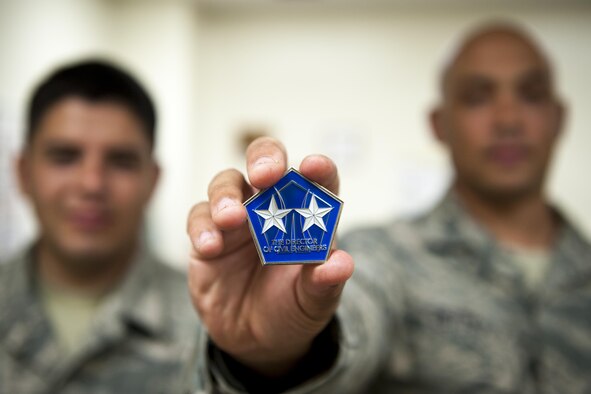 U.S. Air Force Senior Airman Bryan Orozco, 18th Logistics Readiness Squadron mission generation equipment vehicle maintenance journeyman, and Tech. Sgt. Justin Petty, 18th LRS allied trades non-commissioned officer in charge, display a coin presented by Maj. Gen. Timothy Green, the Air Force director of civil engineers, to Petty for his development of a new airfield damage repair anti-corrosion program July 7, 2016. Petty attributes his credit to the Airmen under his charge, who executed the program successfully, setting a new Air Force-wide standard in anti-corrosion maintenance. (U.S. Air Force photo by Senior Airman Peter Reft) (This image was enhanced using multiple filters and dodging and burning techniques)
